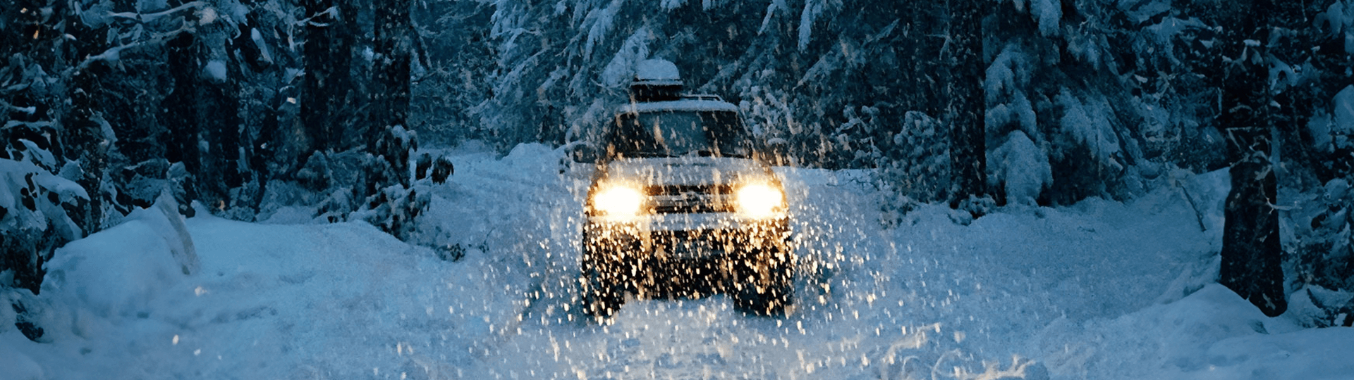 A vehicle driving through the show with a load on top of the vehicle.