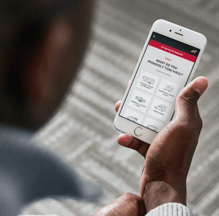 A man holding a phone displaying the Air Lift Help Me Choose tool